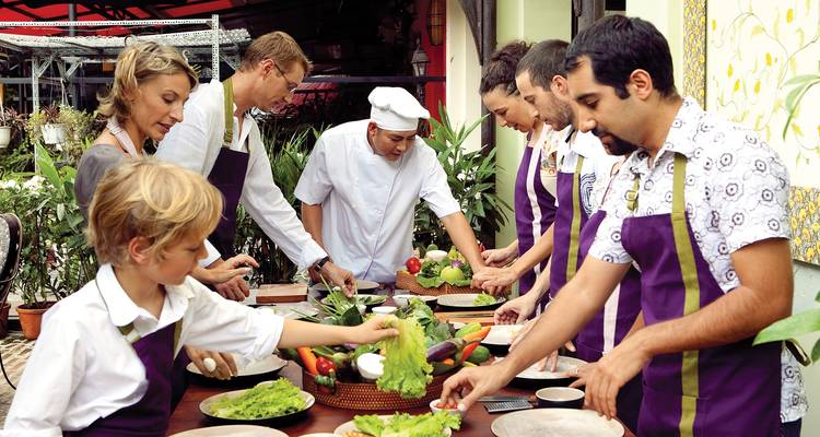 People taking part in an outdoor cooking class with a chef leading.