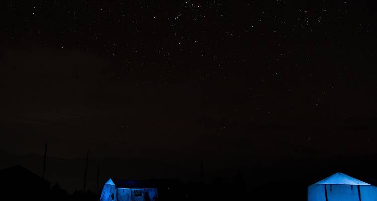 Tienda iluminada bajo un cielo nocturno estrellado.
