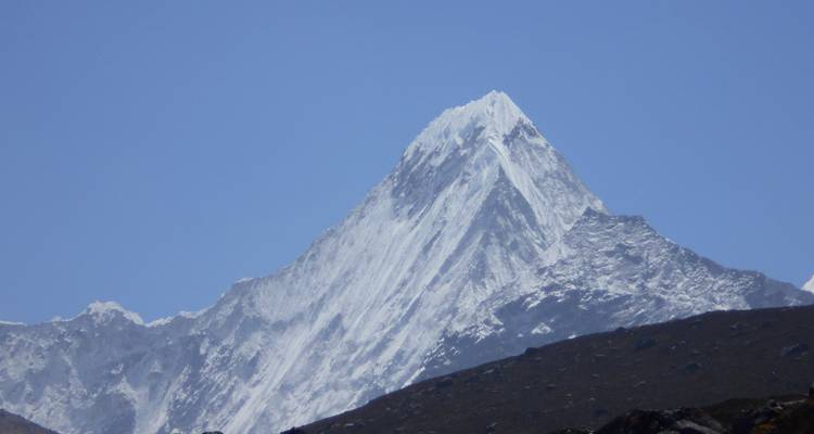 Close-up van een grote, besneeuwde bergtop onder een heldere hemel.
