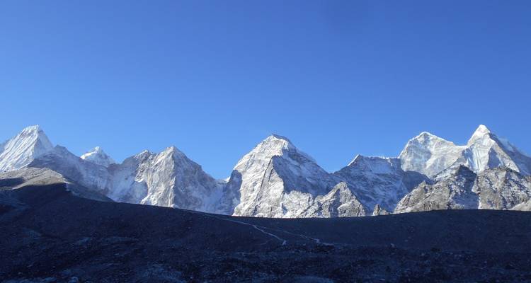 Reeks besneeuwde bergtoppen onder een helderblauwe hemel.