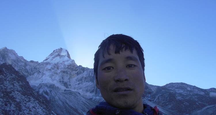 Een persoon die een selfie neemt met een grote berg op de achtergrond.