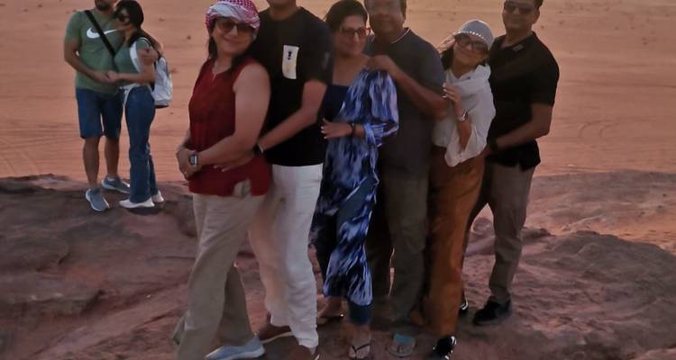 Groupe de touristes posant sur des rochers au coucher du soleil dans un cadre désertique.