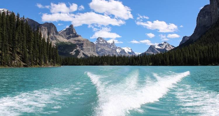 Boat on a turquoise lake with towering mountains.