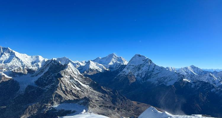 Vue panoramique de montagnes enneigées sous un ciel bleu dégagé.