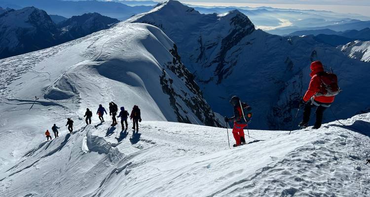 Groupe d'alpinistes descendant une crête enneigée.