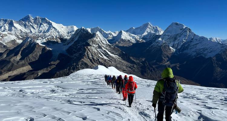Des alpinistes traversant un vaste paysage enneigé.