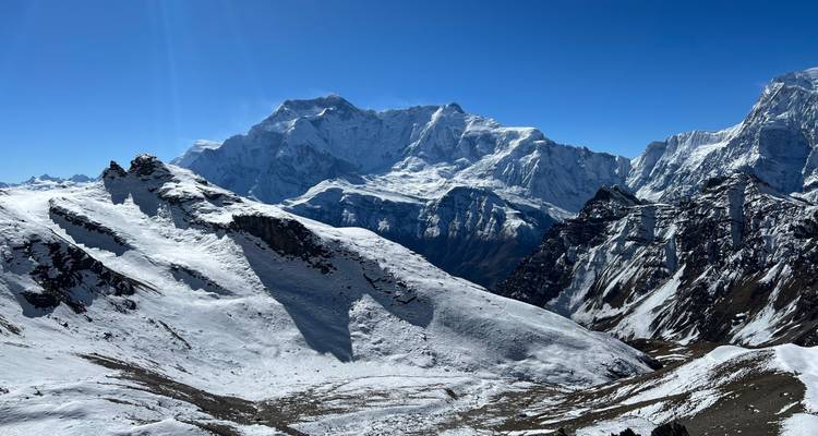 Vue panoramique de montagnes enneigées sous un ciel bleu clair.