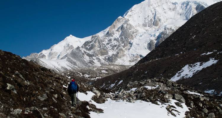 Personne faisant de la randonnée à travers un paysage montagneux enneigé.