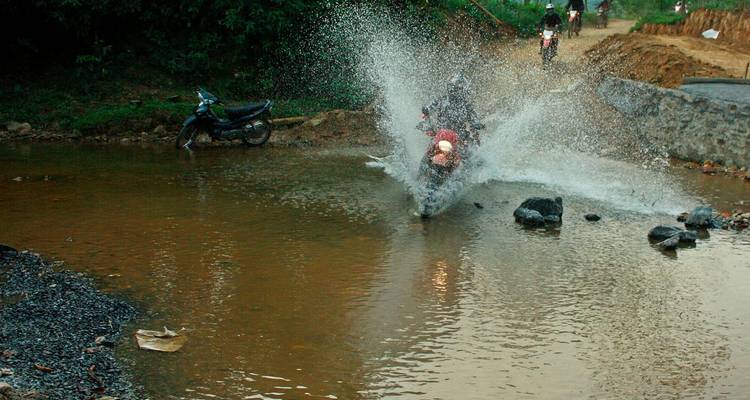 Moto éclaboussant l'eau en traversant une flaque d'eau.