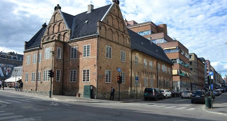 A brick building on a street corner with modern traffic.
