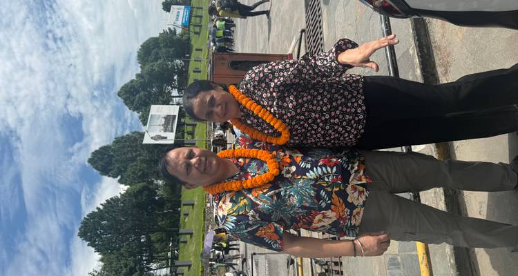 A couple wearing floral garlands posing outdoors.