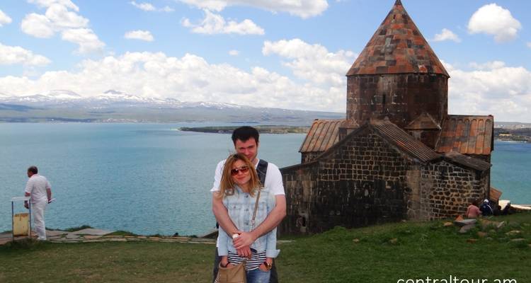 Ein Paar posiert vor einem historischen Gebäude mit einem See im Hintergrund.