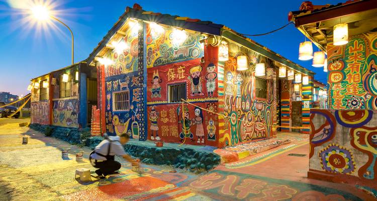 Artiste peignant de l'art de rue coloré dans un village vibrant la nuit.