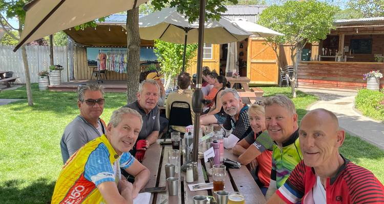Men sitting around a table in a garden setting.