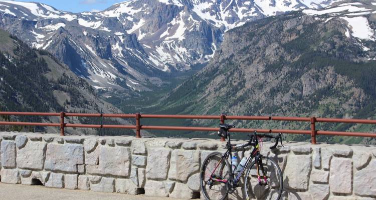 Vélo appuyé contre un mur de pierre avec vue sur la montagne.