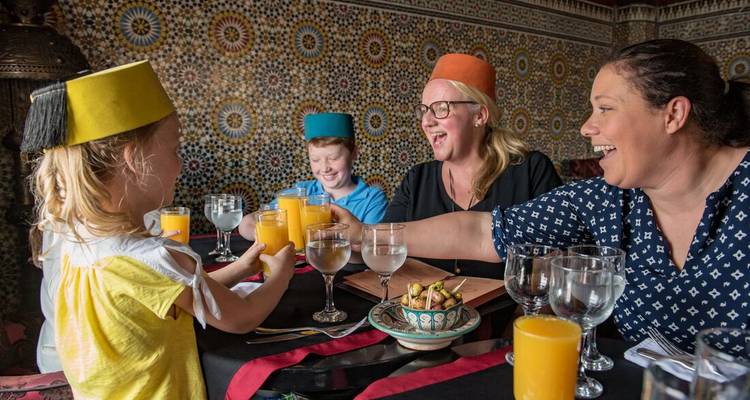 Famille partageant du jus d'orange dans un restaurant marocain orné décoré de carreaux de mosaïque.