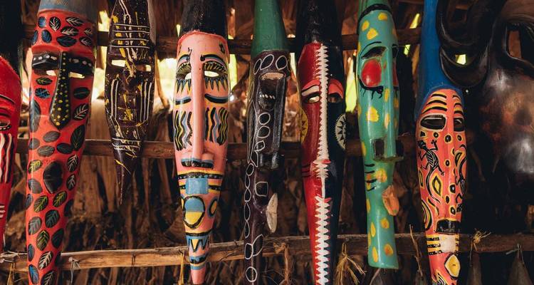 Une collection de masques traditionnels colorés exposés sur un support en bois.