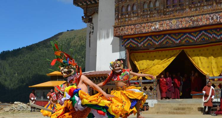 Des danseurs en tenue traditionnelle se produisant devant un temple bhoutanais.
