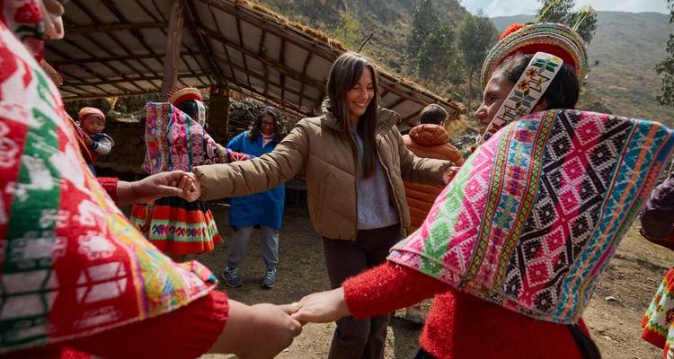 Women dancing and interacting with locals in colorful attire.