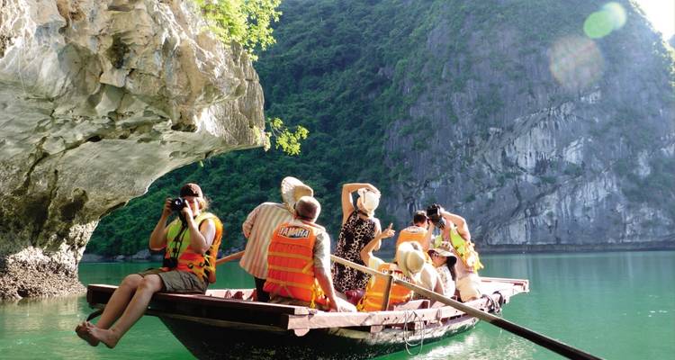 People on a boat tour with limestone cliffs in the background.