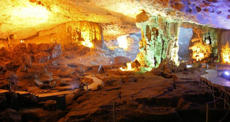 Illuminated cave interior with stalactites and formations.