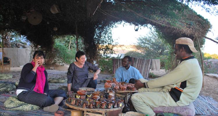People sitting under a shaded area with pottery display.