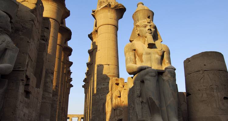Statue of a seated pharaoh among columns.