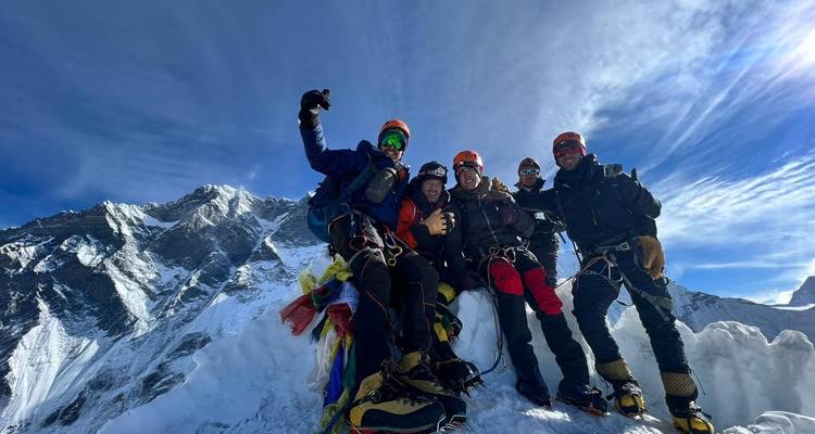 Gruppe von Bergsteigern, die auf einem schneebedeckten Berggipfel posieren.