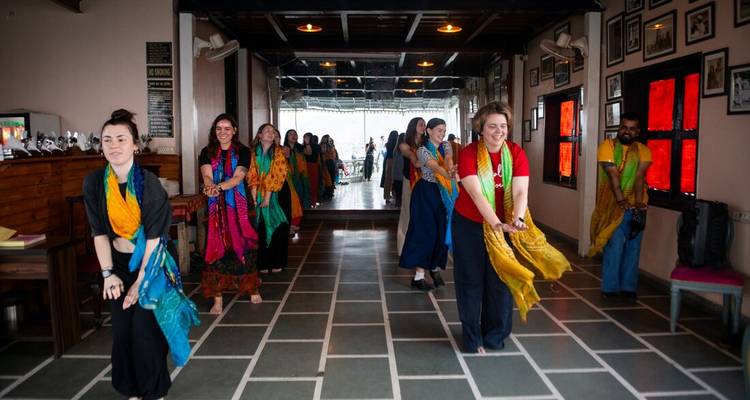 Grupo de personas bailando con ropa colorida dentro de un salón.