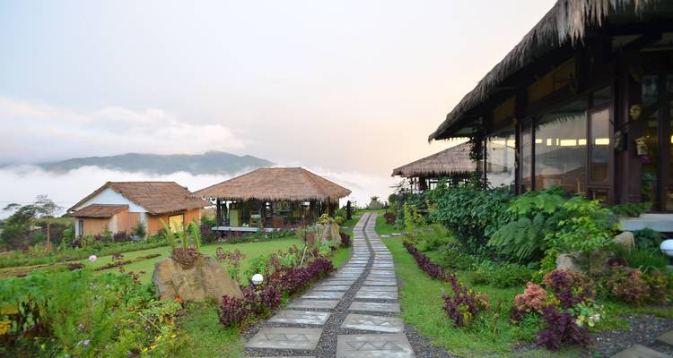 Resort montañoso acogedor con cabañas rodeadas de niebla y colinas.
