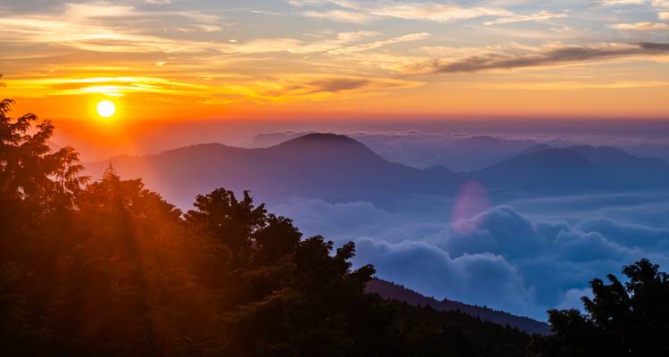Paysage montagneux avec des couches de nuages au coucher du soleil.
