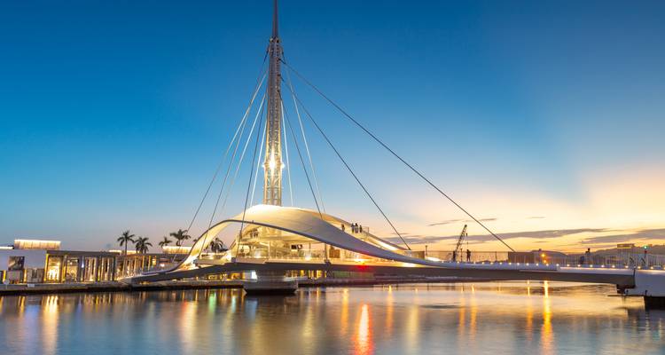 Un pont moderne au-dessus d'un plan d'eau calme au coucher du soleil.