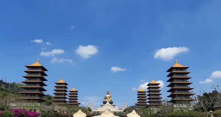 The towering Buddha statue of Fo Guang Shan stands at the end of a grand avenue flanked by eight pagodas under a clear blue sky.