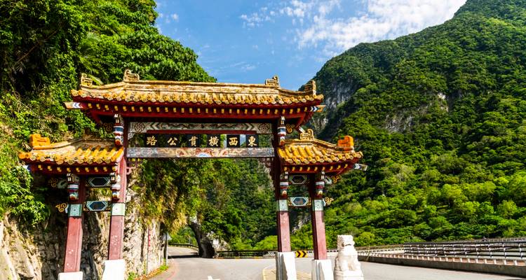 Puerta de arco chino tradicional con las montañas y la exuberante vegetación de la Garganta de Taroko detrás.