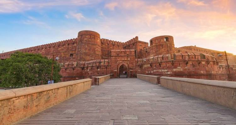 View of a large red fort under a sunset.