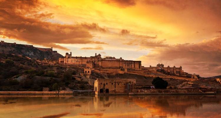 Amber Fort with striking sunset reflection on water.