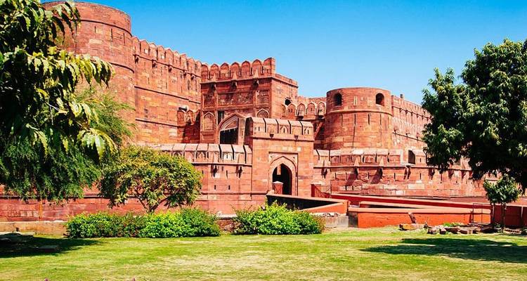 Exterior of a large red fort under clear blue sky.