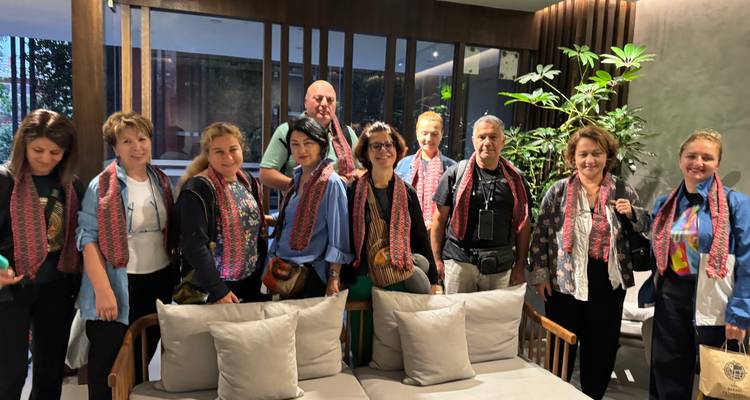 Grupo de personas en el interior usando bufandas, reunidas alrededor de una mesa.