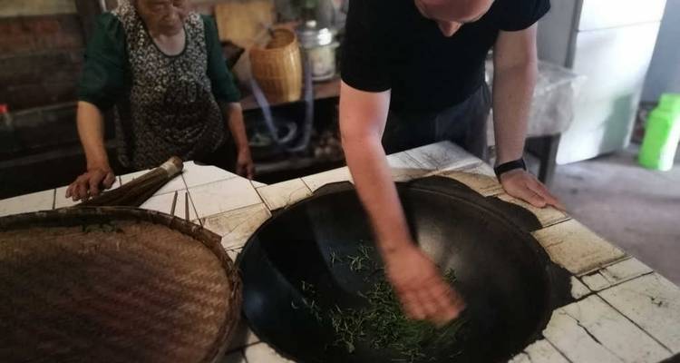 Person, die Teeblätter in traditioneller Umgebung röstet.