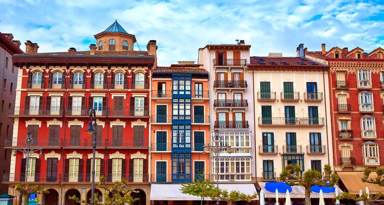 Row of colourful historic buildings with balconies and ornate façades under blue sky.