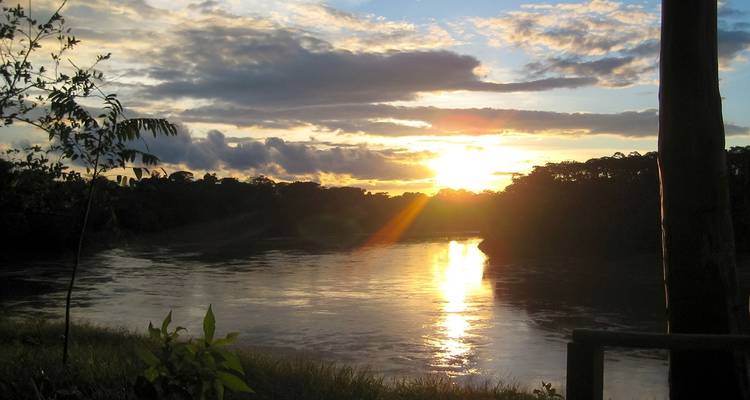 A sunset over a river with trees lining the banks.