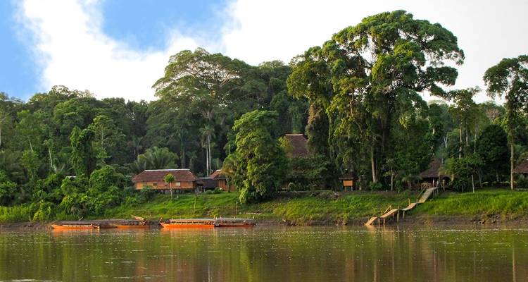 A river scene with orange boats and dense green trees.