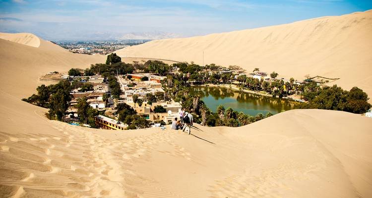 Oasis rodeado de dunas con asentamiento y laguna.