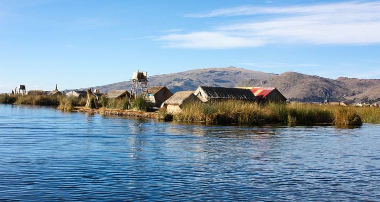 Îles flottantes de roseaux sur un lac avec des montagnes en arrière-plan.