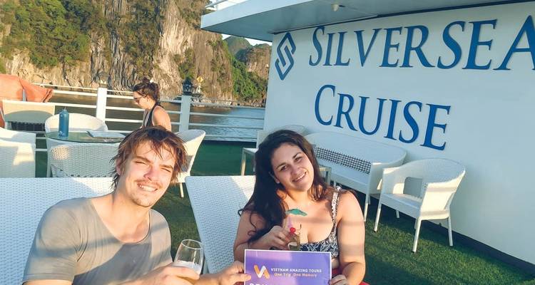 Twee mensen op een cruiseschip met een spandoek en drankjes in de hand.