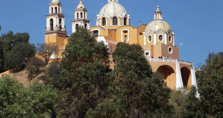 Basilique sur une colline avec des arbres au premier plan.