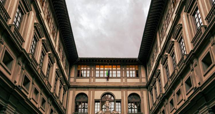 Symmetrischer Innenhof der Uffizien, gerahmt von Renaissance-Architektur unter bewölktem Himmel.