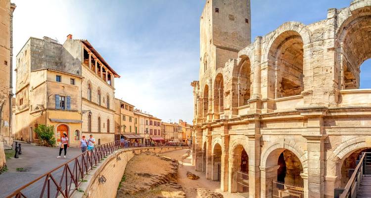 Panoramablick auf das römische Amphitheater von Arles und die umliegenden historischen Gebäude unter einem klaren Himmel.