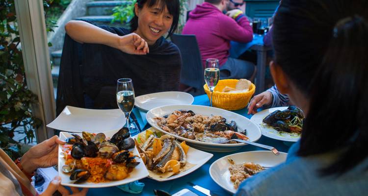 Freunde teilen Teller mit frischen Meeresfrüchten und Wein an einem gemütlichen Restauranttisch.