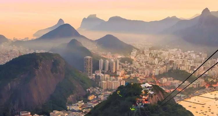 Gouden zonsopgang werpt warm licht over de iconische pieken en het stadslandschap van Rio de Janeiro, gezien vanaf de Suikerbroodberg.